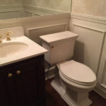 Bathroom remodel, wide mirror, white paneling, brass fixtures